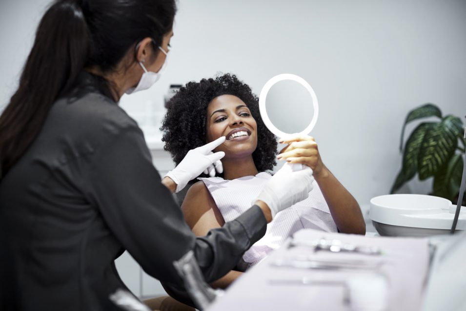 Patient looking teeth in mirror at dental clinic